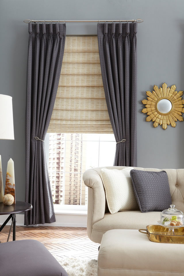 Custom pleated drapery panels in grey fabric hanging in modern living room