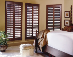 Premium stained wood plantation shutters in living room showing natural basswood grain and louvers