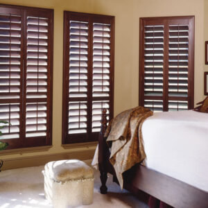 Premium stained wood plantation shutters in living room showing natural basswood grain and louvers