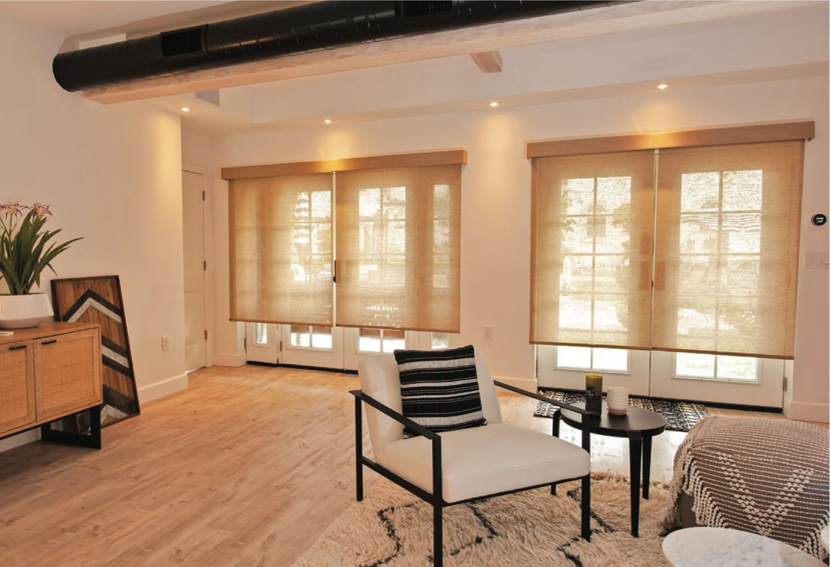 Perfect light filtering sheer and natural roller shades in warm tone installed on living room windows